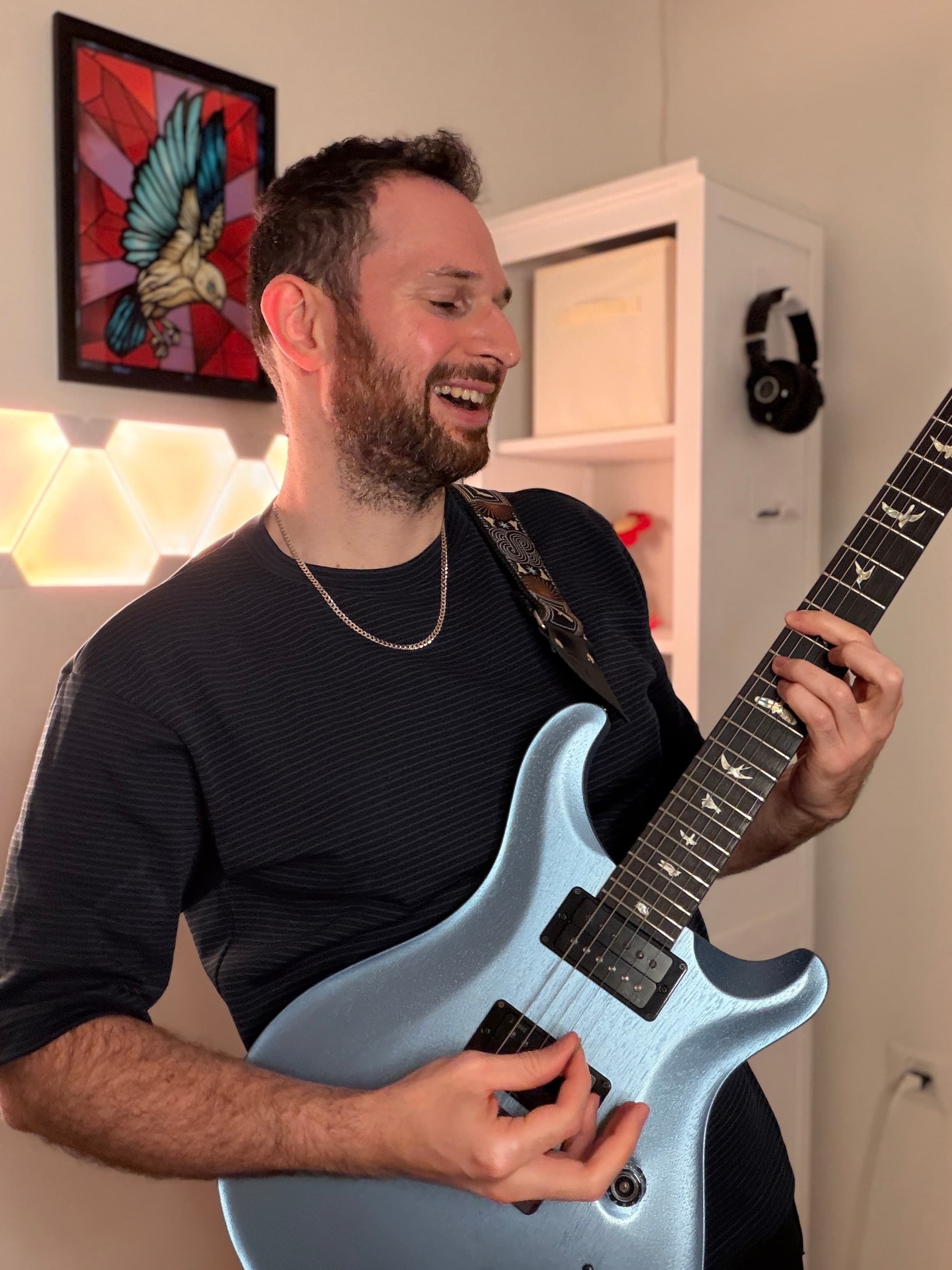 Lior playing his blue PRS guitar in his home studio